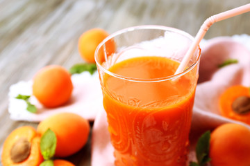 Glass of apricot juice and fresh fruits on table close up