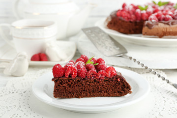 Piece of cake with chocolate Glaze and raspberries on color wooden background