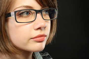 Attractive young woman with glasses on gray background