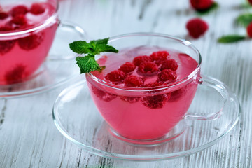 Cups of raspberry drink with berries on wooden table close up