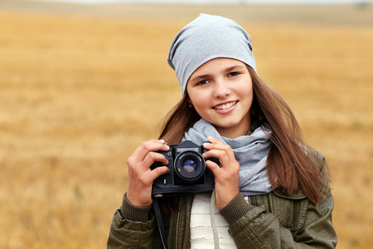 Beautiful smiling teenage girl holding vintage photo camera