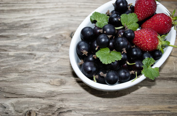 Jostabeeren, Ribes nidigrolaria und Erdbeeren n weißer Schale auf Treibholz / Holz Brett 