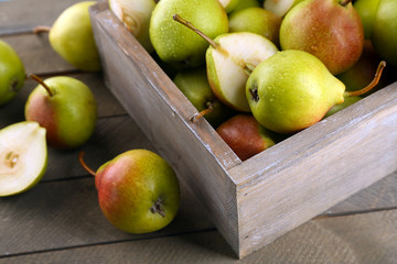 Ripe pears in wooden box on table close up