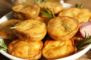 Delicious baked potato with rosemary in bowl on table close up