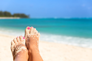 Holiday concept. Woman feet close-up relaxing on beach, enjoying