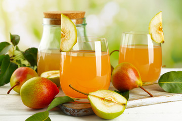 Glass of juice with fresh pears on wooden table on blurred background