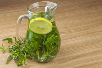 Fresh homemade mint tea. Tempting summer refreshment. Healthy, refreshing drink without sugar. Peppermint tea in a glass jar with lemon. Preparing tea.
