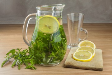Fresh homemade mint tea. Tempting summer refreshment. Healthy, refreshing drink without sugar. Peppermint tea in a glass jar with lemon. Preparing tea.
