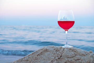 Romantic glass of wine sitting on the beach at colorful sunset
