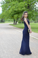 Fototapeta premium Beautiful formally dressed young woman standing outside in park