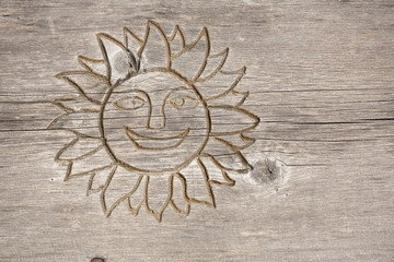 Smiling sun carved into wood