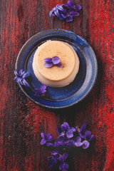 Caramel pannacotta with violet flowers