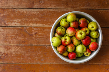 Results of the harvest. Full basin of apples on wooden floor