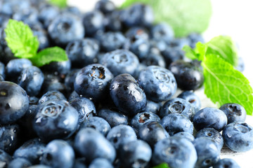 Tasty ripe blueberries with green leaves close up