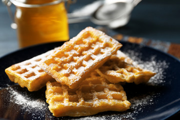 Sweet homemade waffles on plate, on dark wooden background