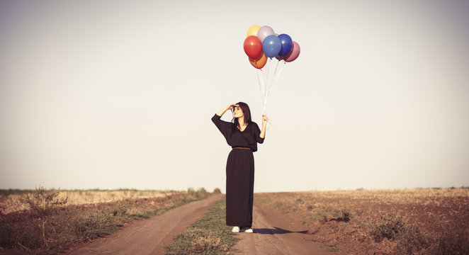 girl in black dress with multicolored balloons