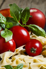 Dry Italian pasta farfalle, tomato and basil, selective focus
