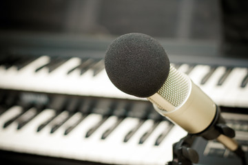 Close up on a microphone during recording session with a singer, piano in the background