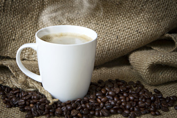 Coffee cup and coffee beans on sack.
