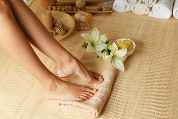 Fototapeta na wymiar Female feet on soft towel over bamboo mat background