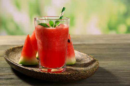 Glass of watermelon juice on wooden table on blurred background