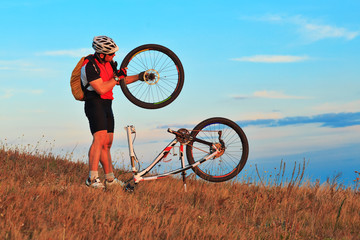 Man cyclist repairing a bike  against blue sky