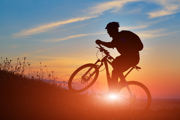 Fototapeta na wymiar Silhouette of a biker and bicycle on sky background.