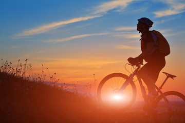 Fototapeta premium Silhouette of a biker and bicycle on sky background.