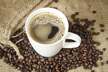 Coffee cup and coffee beans on sack.
