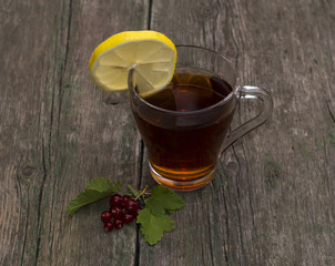 the transparent cup of tea with a lemon decorated with currant