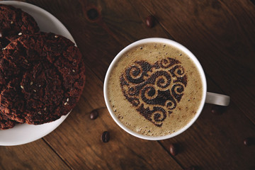 Cup of coffee with cookies and coffee beans on wooden table, top view