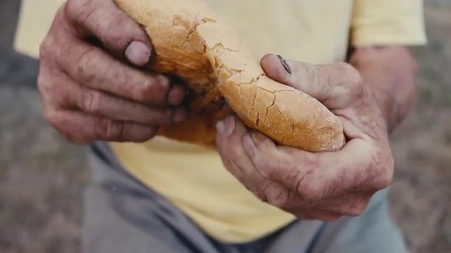 A loaf of bread in an old mans hands