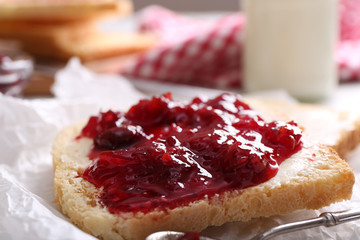 Bread with butter and homemade jam on crumpled parchment, closeup