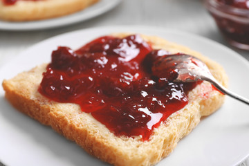 Bread with butter and homemade jam in white plate, closeup