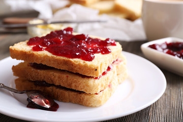 Bread with butter and homemade jam on wooden table, closeup