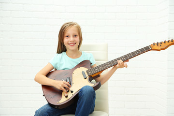 Fototapeta premium Little girl playing guitar on light background