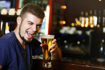 Young man drinking beer in bar