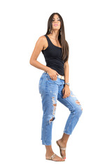 Young casual woman in torn jeans posing at camera.