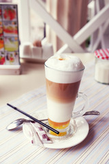 Glass of hot cappuccino on table in cafe