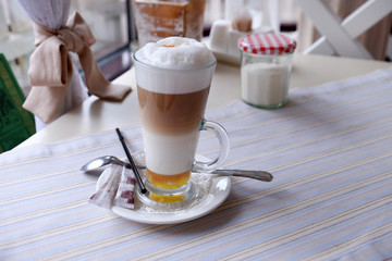 Glass of hot cappuccino on table in cafe