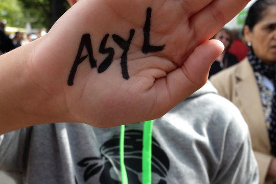 Ein Kind h&auml;lt die Hand hoch, auf der "Asyl" geschrieben steht