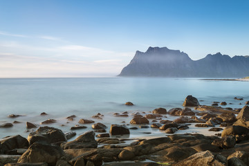 A view of the rocky beach Uttekleiv Lofoten. Blurry effect of water surface with long exposure.