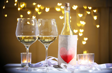 Wine glass near bottle on hearts bokeh background