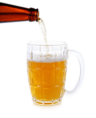 Beer is poured from a green bottle into a glass, isolated on whi