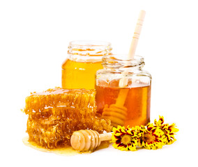 Sweet honeycomb and two jars of honey with stick and flowers