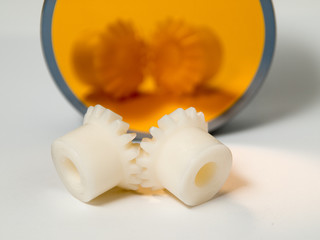 Bevel gear-wheels before a golden mirror isolated against a white background.