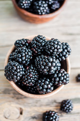 Fresh sweet blackberry in clay pots on a wooden table, closeup