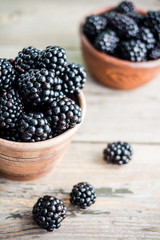 Fresh sweet blackberry in clay pots on a wooden table, closeup
