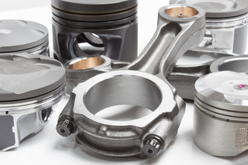 a set of pistons and rods for automobile engine on a white background