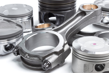 a set of pistons and rods for automobile engine on a white background